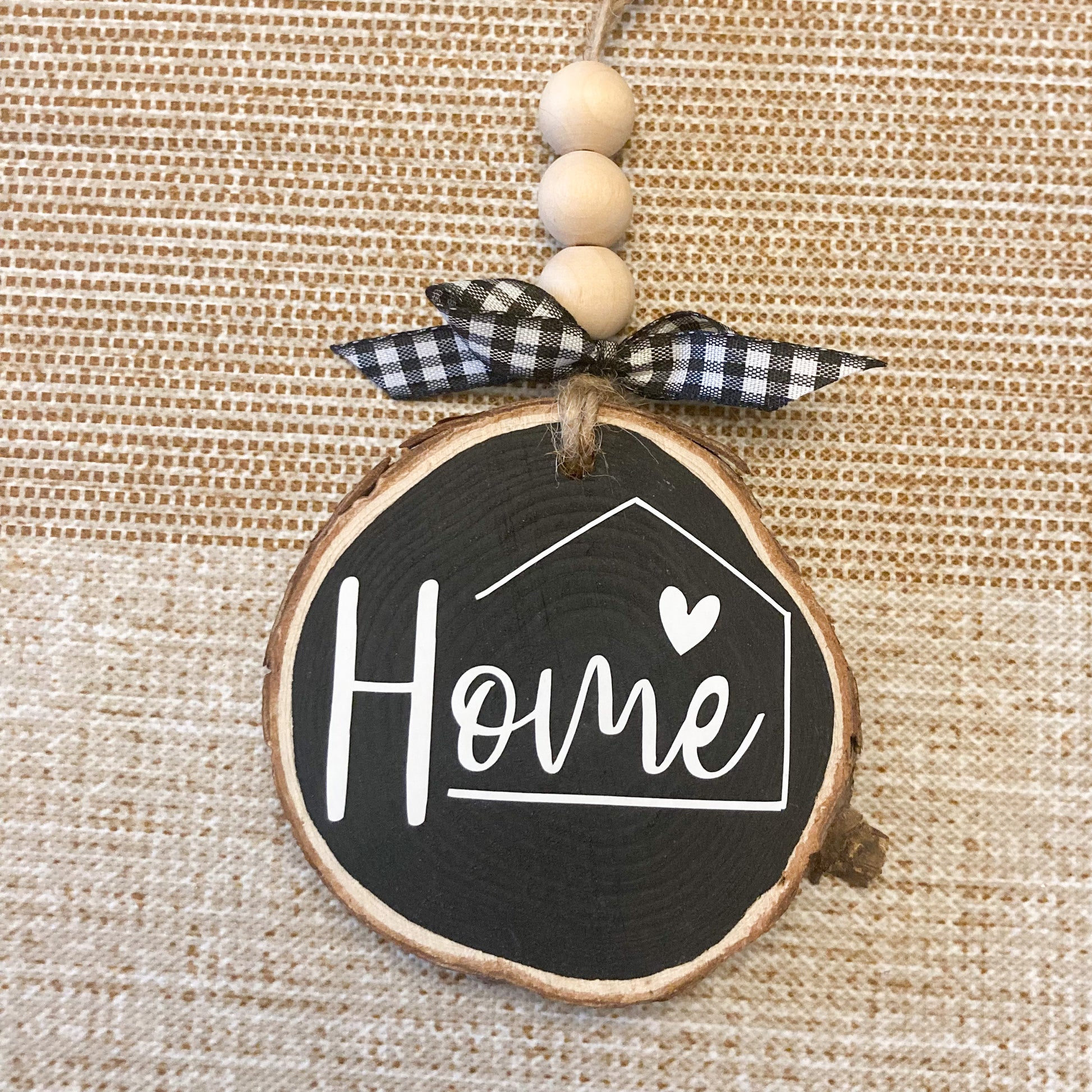Handmade home ornament on 3 inch wood round painted black with white vinyl word Home jute twine hanger with wood beads and buffalo checkered bow