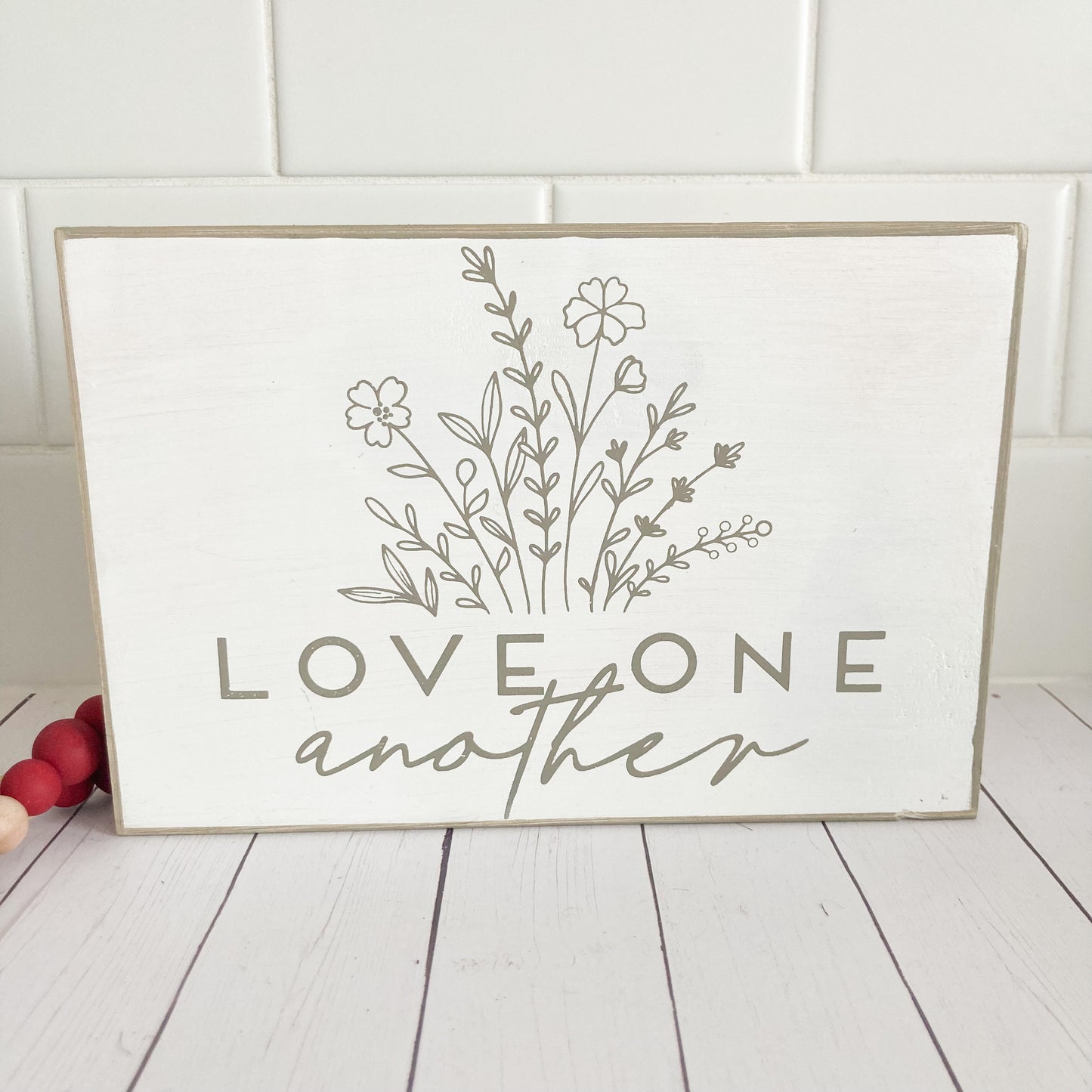 Handmade wood sign painted distressed white with flowers and words saying love one another in tan 5.5 inches by 8 inches