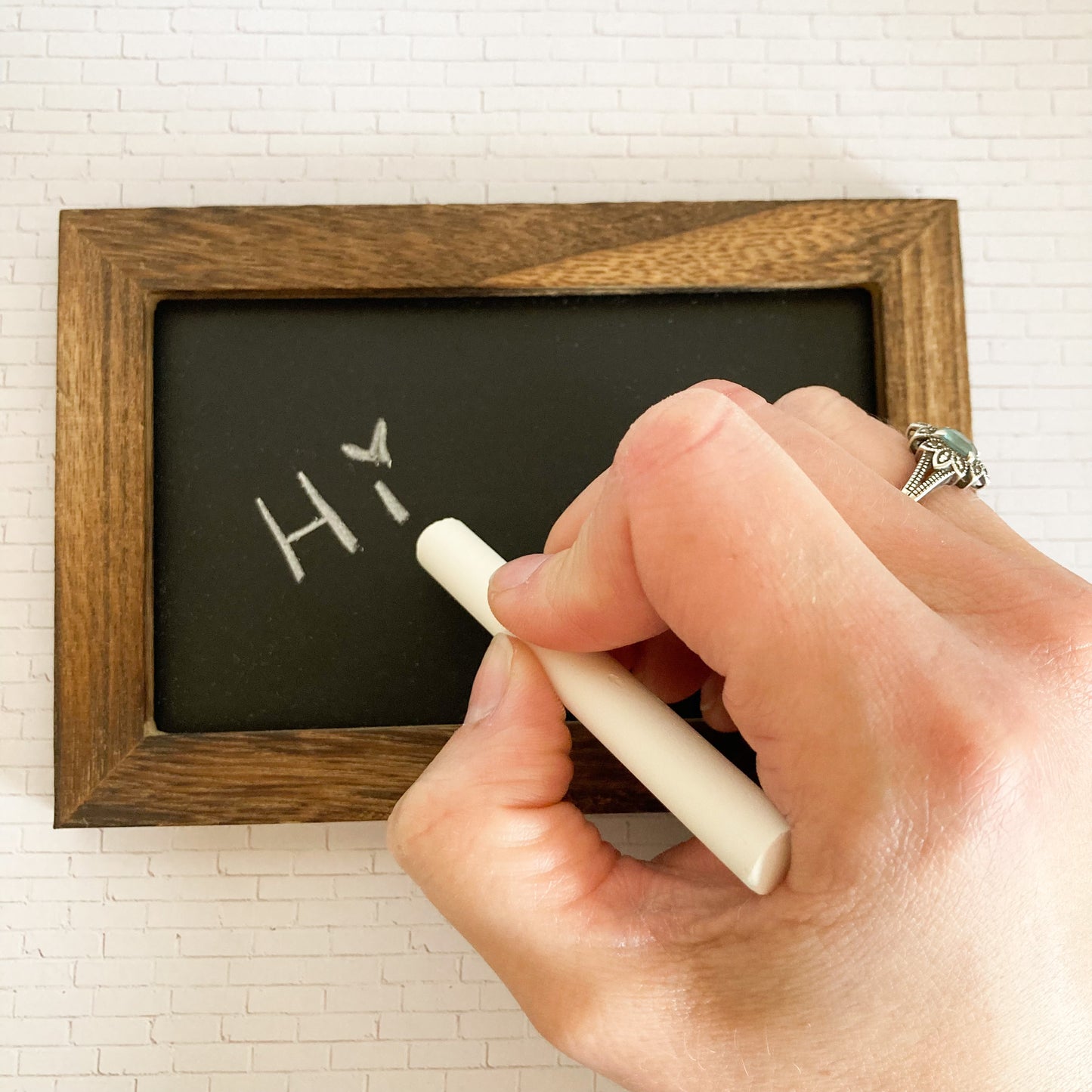 Hand writing Hi using chalk on Mini chalkboard 4 inches by 6 inches with wood frame stained brown real chalkboard slate