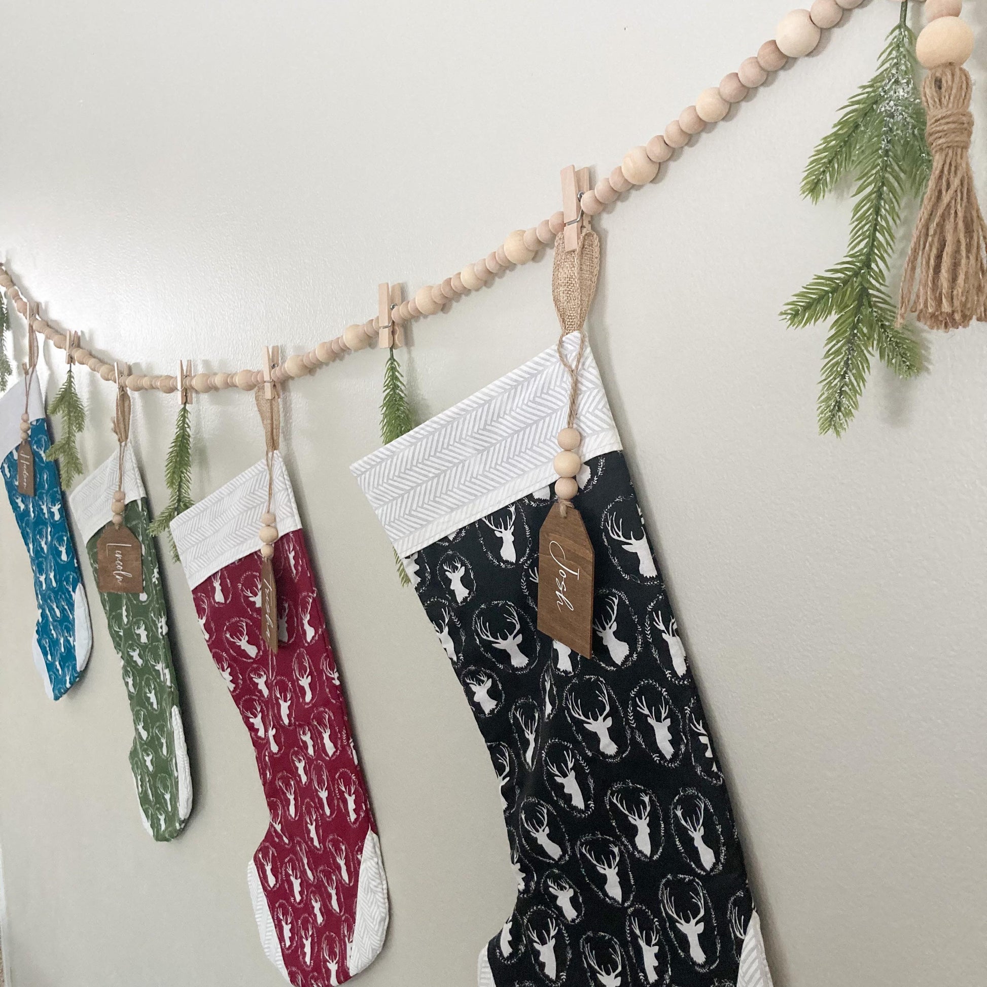 Handmade Wood bead garland display with jute twine tassels and 9 mini clothespins 6.5" total length hanging on wall displaying stockings